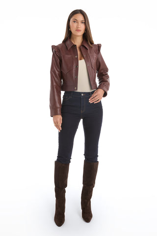 A woman stands facing forward against a white background, wearing the Chantal Ruffle Sleeve Leather Jacket in Espresso as a fall statement piece, paired with a light top, dark skinny jeans, and knee-high dark suede boots.