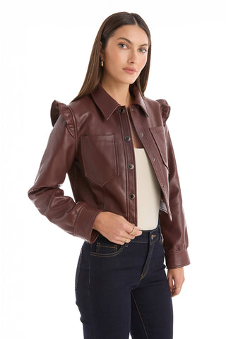 A woman with long brown hair wears the Chantal Ruffle Sleeve Leather Jacket in Espresso over a beige top and dark jeans, standing against a white background for a chic fall statement look.