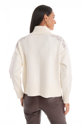 A woman with straight dark hair is seen from the back, wearing the Camille Lace Turtleneck Sweater in Pearl, featuring delicate lace details on the shoulders and sleeves, paired with dark brown pants.