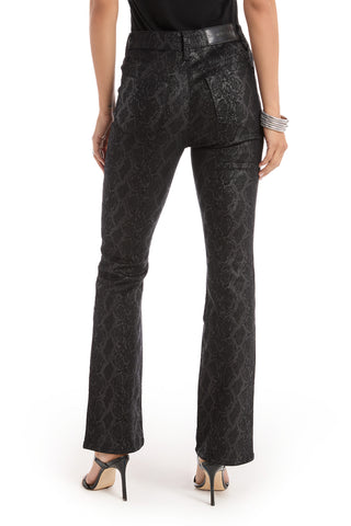 A person wearing Aria Coated Flare Jean - Python pants, a black belt, black top, silver bracelets, and black heeled sandals, shown from the back against a white background.