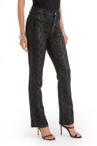 A person in Aria Coated Flare Jean - Python, with a high-waisted snakeskin pattern, a black top, black high-heeled sandals, and silver bangles stands against a white background.