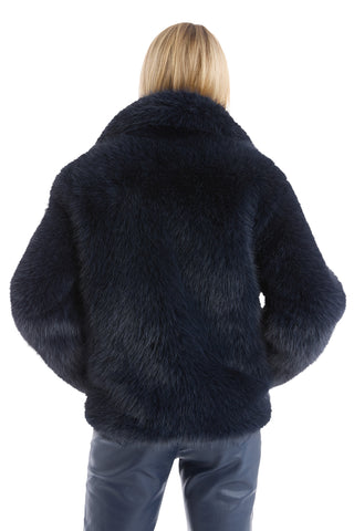 A person with blonde hair, seen from behind, models the cruelty-free Dani Fur Coat in Navy and matching pants against a white background.