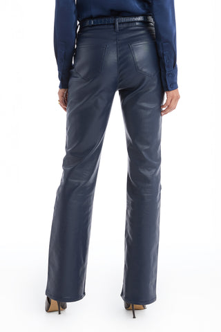 A person wearing navy Aria Coated Flare Jeans with a high-rise fit, paired with a matching blue long-sleeve shirt and beige heels, stands facing away from the camera.