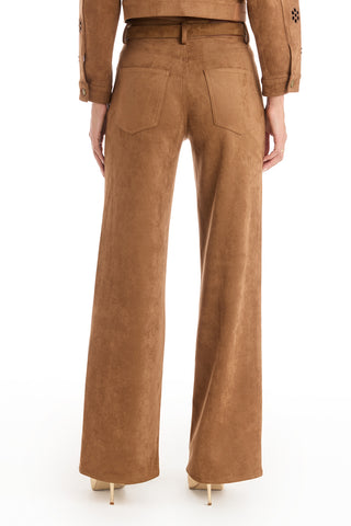 Model shown from the back wearing the Kaia Suede High Rise Jean in Cognac, featuring straight legs and two back pockets. Paired with beige high heels; only lower torso and legs are visible.