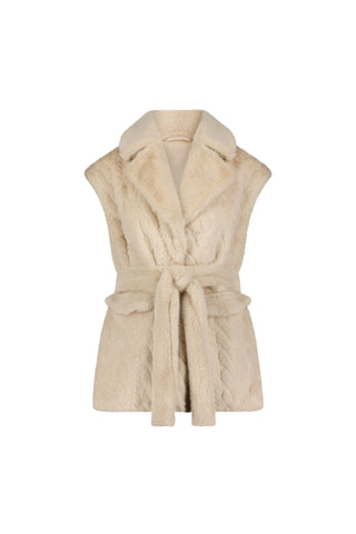 The Leone Cable Knit Cardigan in Pearl is a sleeveless, beige faux fur vest with a wide collar and tie-waist belt, offering cozy style similar to classic cable knits, shown on a white background.