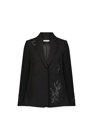 The London Floral Sequin Blazer - Black is a slim-fit blazer with a single button, two front pockets, and elegant floral appliqué detailing on the shoulder, sleeve cuffs, and near one pocket, shown on a plain white background.