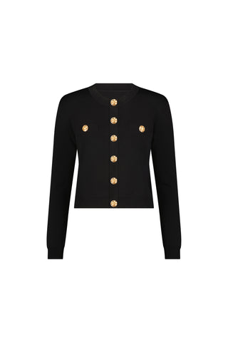 The Loretta Knit Cardigan Top in black features padded shoulders, a round neckline, gold dome buttons down the front, and two chest pockets, shown on a plain white background.