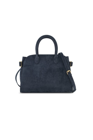 The Margo Suede Bag - Blue is a dark navy faux suede handbag with two handles, a detachable crossbody strap, and gold-tone hardware, shown against a white background.