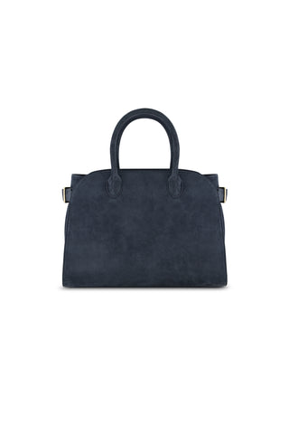 The Margo Suede Bag - Blue, a dark navy faux suede handbag with two rounded handles, a structured rectangular shape, and a detachable crossbody strap, is displayed against a plain white background.