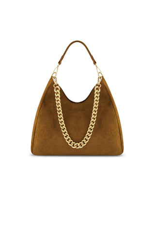 The Tribeca Chain Suede Bag - Cognac features brown suede, a wide base, curved top, and short handle. A chunky gold chain drapes across the front, standing out against the plain white background.