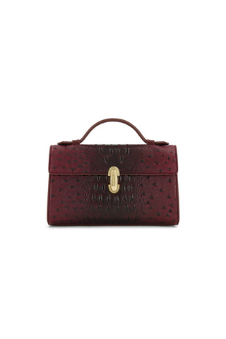 The Danica Ostrich Clutch in Merlot features a crocodile texture, top handle, and gold clasp, shown against a white background.