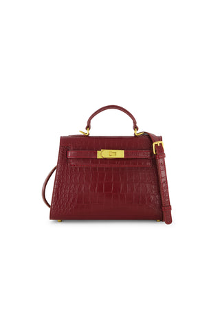 The Kayla Croco Handbag - Merlot is a structured, dark red crocodile leather bag featuring a top handle, gold hardware, and a detachable shoulder strap, shown against a plain white background.