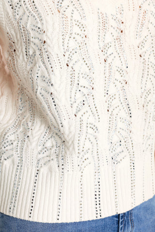 Close-up of the Mikaela Crystal Knit Tank in white, featuring a textured knit pattern and sparkling rhinestone embellishments, paired with light blue denim jeans.