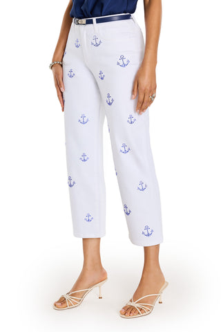 A person wears the Kelsey Cropped Jean - Crystal Anchors, featuring blue anchor prints, paired with a navy top, silver belt, and heeled sandals. The flattering high-rise silhouette is showcased against a white background.