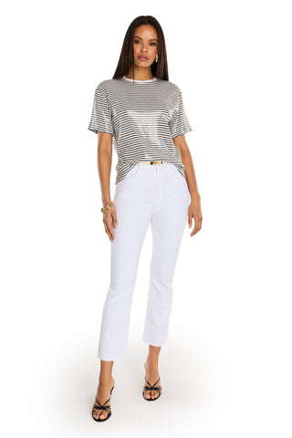 A woman stands facing forward against a white background, wearing the Miranda Sequin T-Shirt in navy stripe, high-waisted white cropped pants, black strappy heels, and gold bracelets.