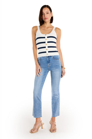 A woman with shoulder-length dark hair poses against a white background wearing the Ruth Button Tank - Navy Stripe, light blue jeans, and beige heeled sandals.