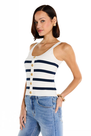 A woman with straight brown hair models the Ruth Button Tank - Navy Stripe with gold dome buttons and light blue jeans. She stands sideways, one hand in her pocket, against a white background.