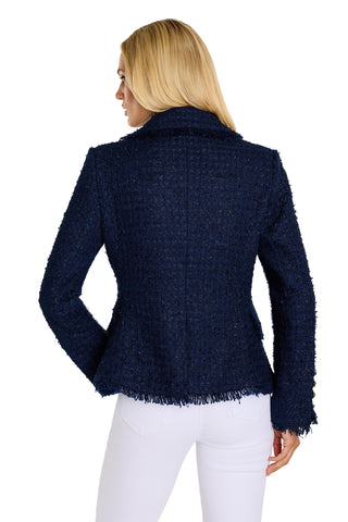 A woman with straight blonde hair, seen from the back, wears the Giselle Single Breasted Tweed Blazer in navy with gold knot buttons and frayed edges, paired with white pants against a plain white background.