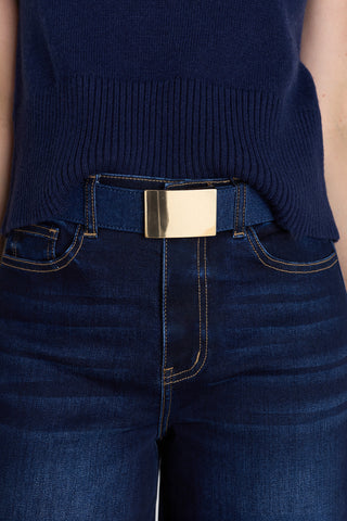 The Bianca Belt in dark wash worn at the waist, showing the denim strap and gold buckle