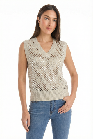 A woman wears the Addison Sequin Crochet Top in Pearl, a beige sleeveless knit with a V-neck over a nude top, paired with blue jeans. She stands against a white background, looking at the camera with long, straight hair.