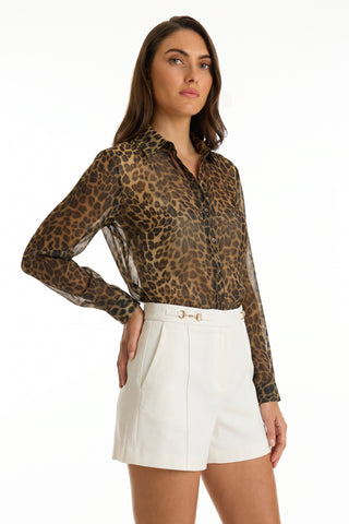 A woman with long brown hair wears the Ana Chiffon Blouse in leopard print, styled with high-waisted white shorts and a belt, standing against a plain white background.