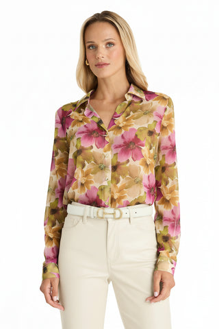 A woman stands against a white background wearing the Ana Chiffon Blouse - Floral Print with long sleeves, paired with high-waisted ivory pants and a white belt.