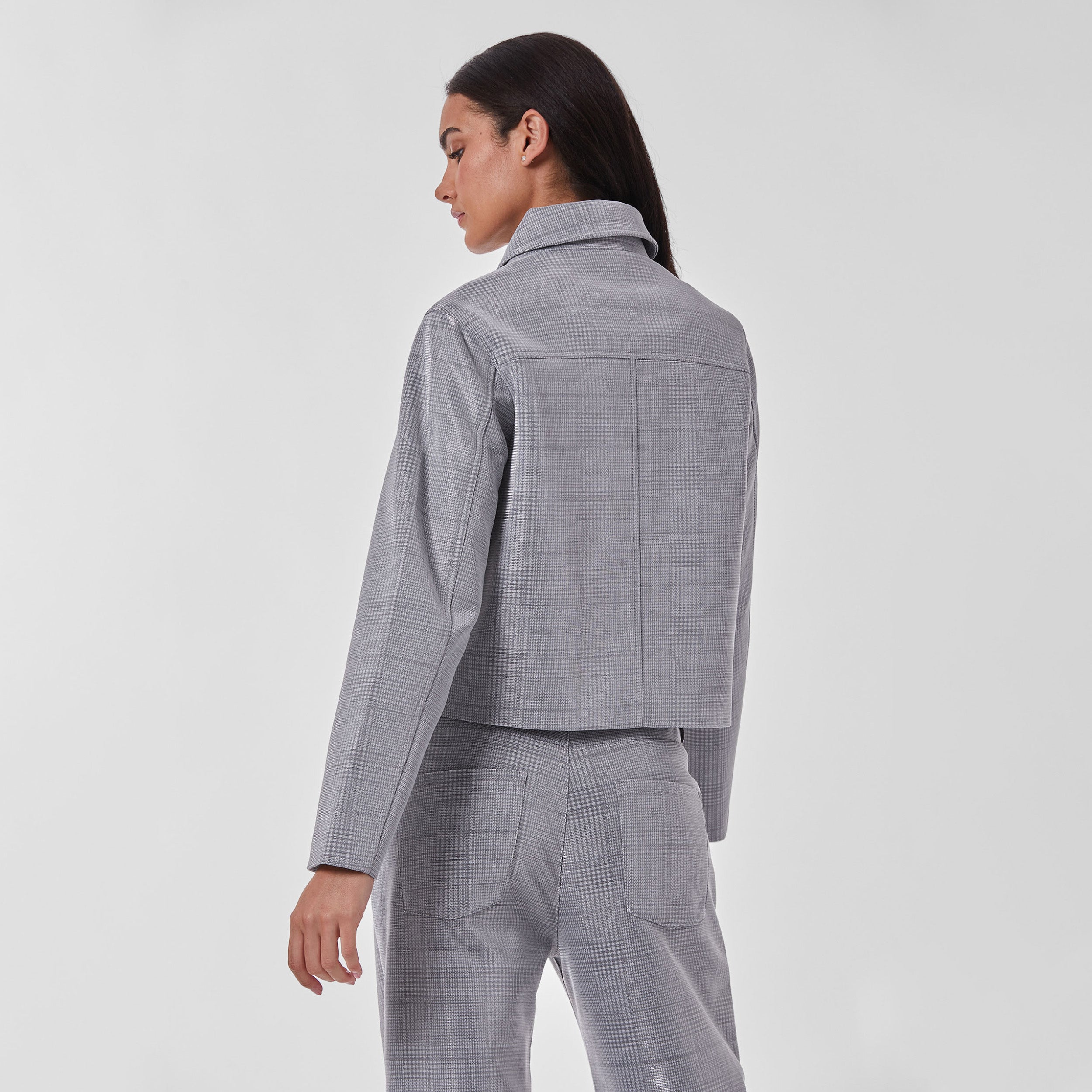 Rear view of woman wearing silver plaid patterned cropped jacket and matching pants.