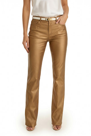 A person wearing the Aria Coated Flare Jean in Gold Metallic, paired with a white sleeveless top and open-toe heels, stands against a plain white background.