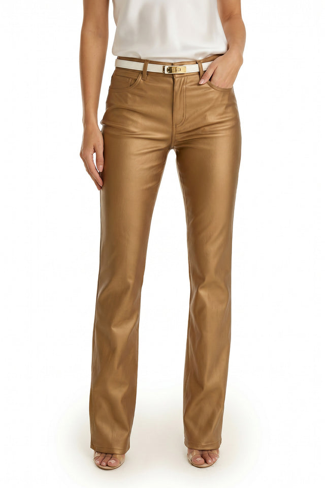 A person wearing the Aria Coated Flare Jean in Gold Metallic, paired with a white sleeveless top and open-toe heels, stands against a plain white background.