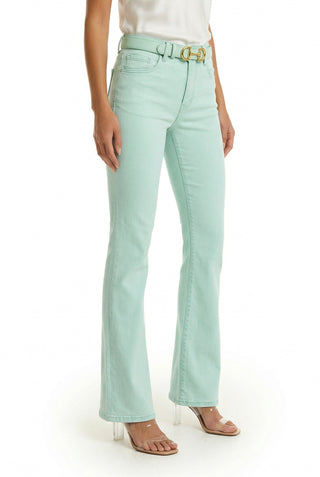 A person wearing the Aria Flare Jean - Mint with a matching belt, white sleeveless top, and clear-heeled sandals stands against a white background.