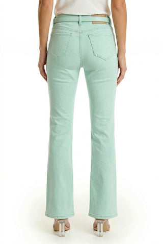 A person is shown from the back wearing the Aria Flare Jean - Mint, a pair of high-rise mint green denim jeans, with clear-heeled shoes, standing against a plain white background.