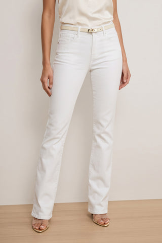A person wearing the Aria Flare Jean - White with a white belt, a cream sleeveless top, and beige open-toed heels stands against a neutral background. The person's head is not shown in the image.