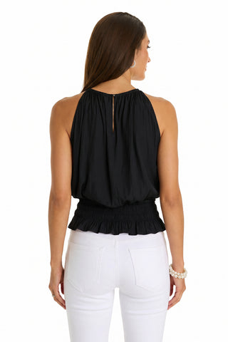 Woman facing away, wearing the Betsy Halter Top in black with a gathered neckline and ruffled waist, paired with fitted white pants. She has long brown hair and a beaded bracelet, giving this classic top a modern twist.