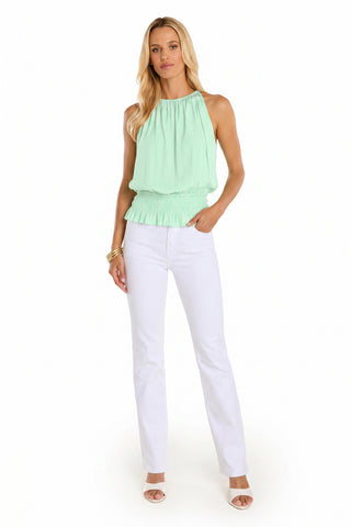 A woman with long blonde hair wears the Betsy Halter Top - Mint against a white backdrop, paired with white pants, heeled sandals, and gold bracelets.