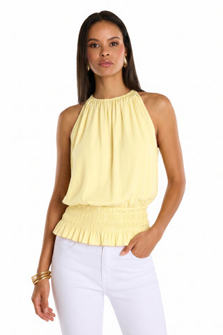 A woman wears the Betsy Halter Top - Sunshine Yellow with a gathered neckline and smocked waist, styled with white pants, gold hoop earrings, and bangles—an effortlessly chic summer look on a white background.