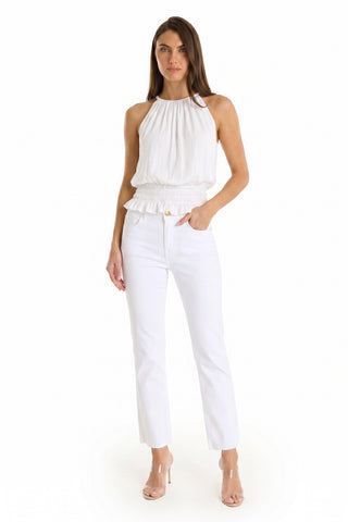A woman with long straight brown hair and a neutral expression wears the Betsy Halter Top - White against a white backdrop, styled with white straight-leg pants and clear heels for an effortlessly chic resort look.