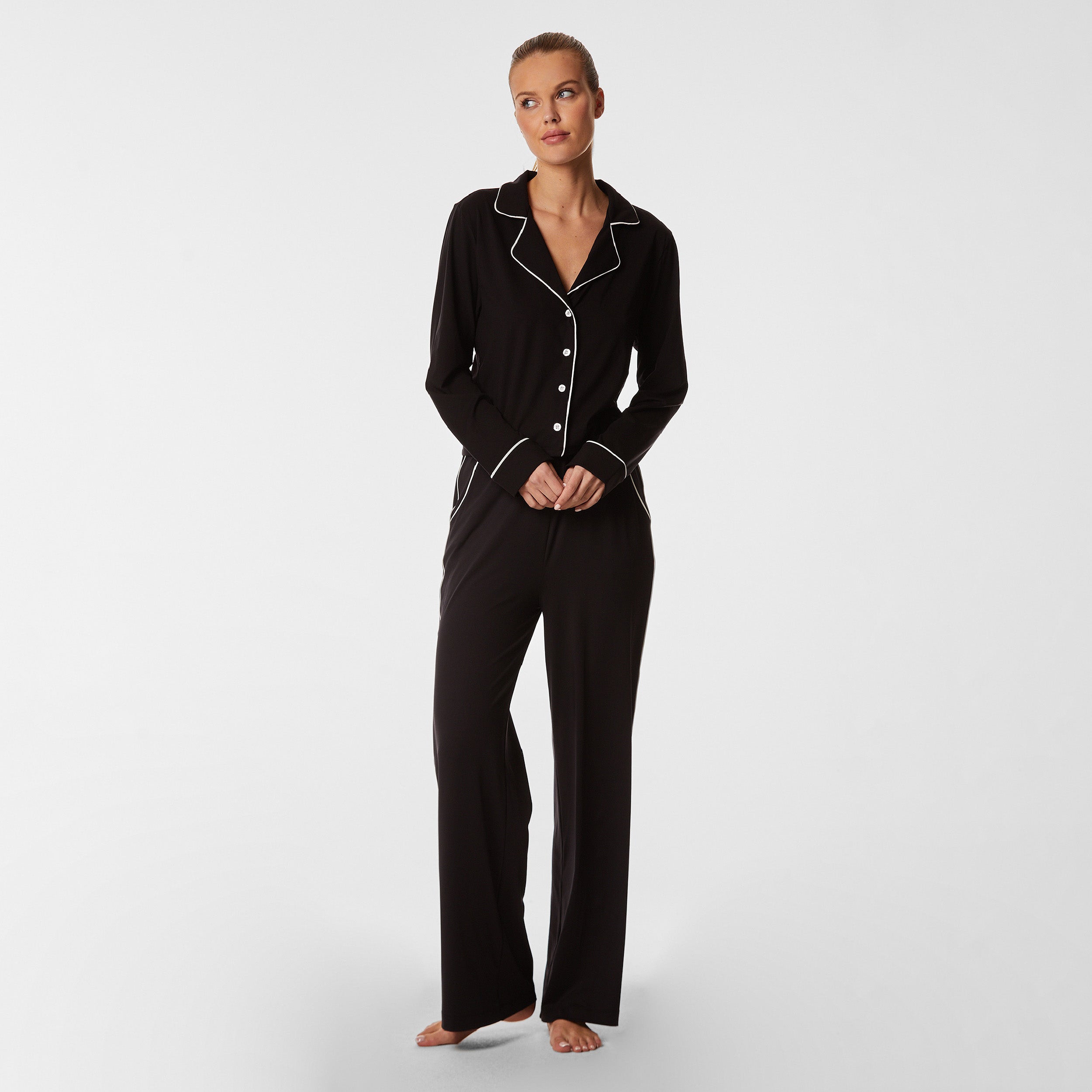 Full front view of woman wearing soft Black Pajama set with white piping detail.