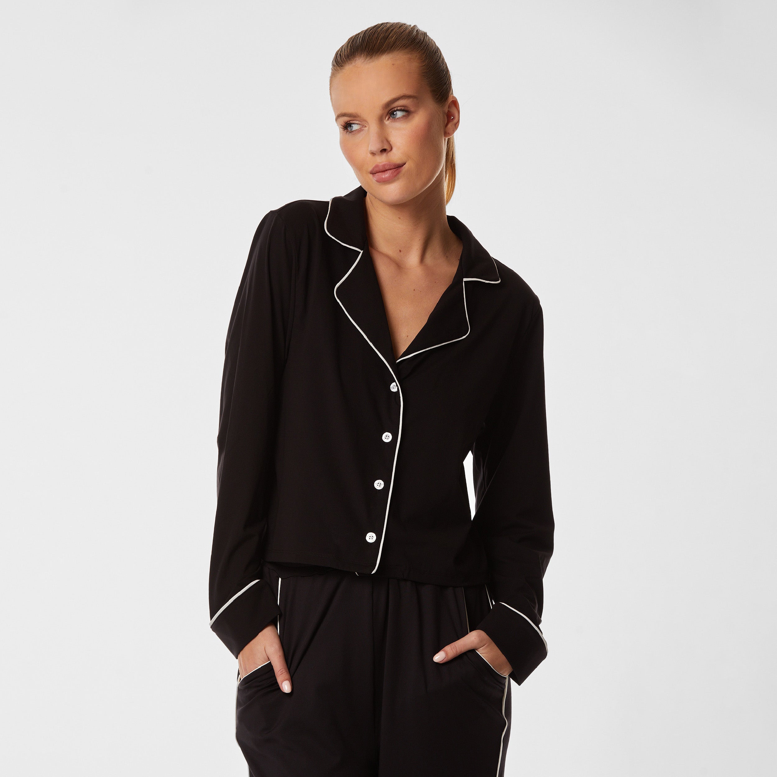 Front view of woman wearing soft Black Pajama shirt with white piping detail and white buttons.