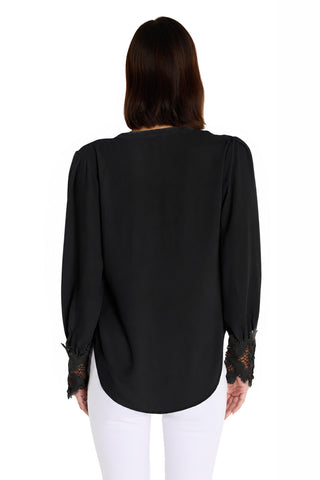 A person with dark, shoulder-length hair is seen from the back, wearing the Blake Lace Sleeve Blouse in black with white pants, standing against a plain white background.