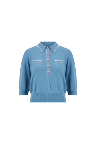The Bobbi Polo Shirt in Serene Blue features short sleeves, a collared neckline, button-down front, two chest accents with buttons, ribbed hem, and contrasting light blue trim for an elevated casual look.