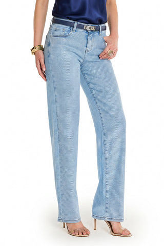A person wears high-rise wide-leg Brynn Crystal Jean - Medium Blue, a dark blue satin top, black belt, heeled sandals, and gold jewelry against a white background. Their face is not shown.