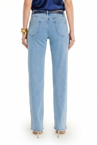 Someone wearing the Brynn Crystal Jean - Medium Blue, a dark top, nude heels, and gold accessories faces away, highlighting the crystal-accented back pockets of the jeans against a plain white background.