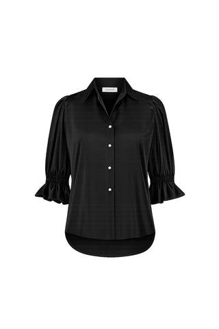 The Cindy Ruffle Sleeve Shirt - Black features a lightweight design with a collar, gold front buttons, three-quarter ruffle sleeves with ruffled cuffs, and a curved high-low hem, shown on a white background.
