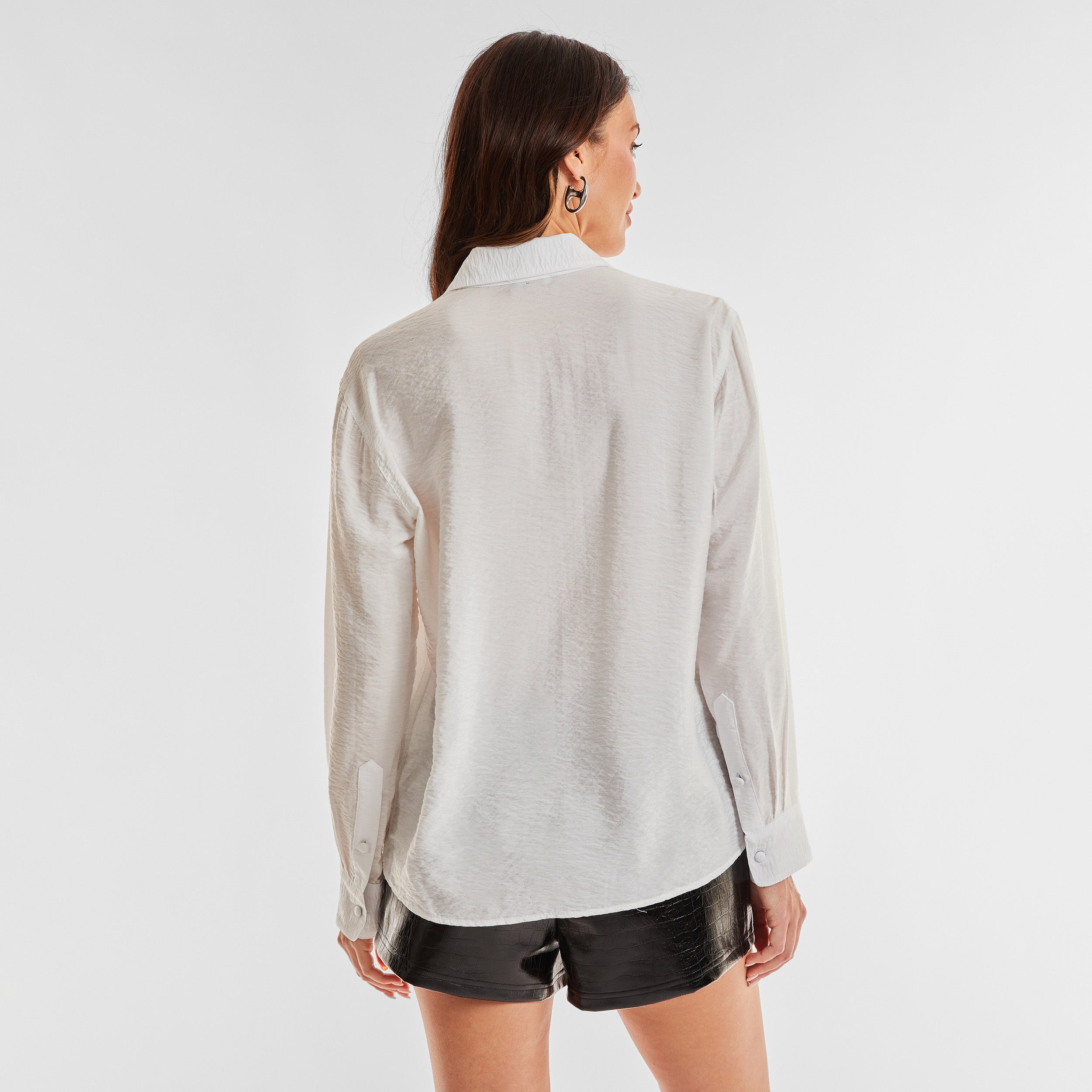 Rear view of woman wearing sheer and textured long sleeve button up top.