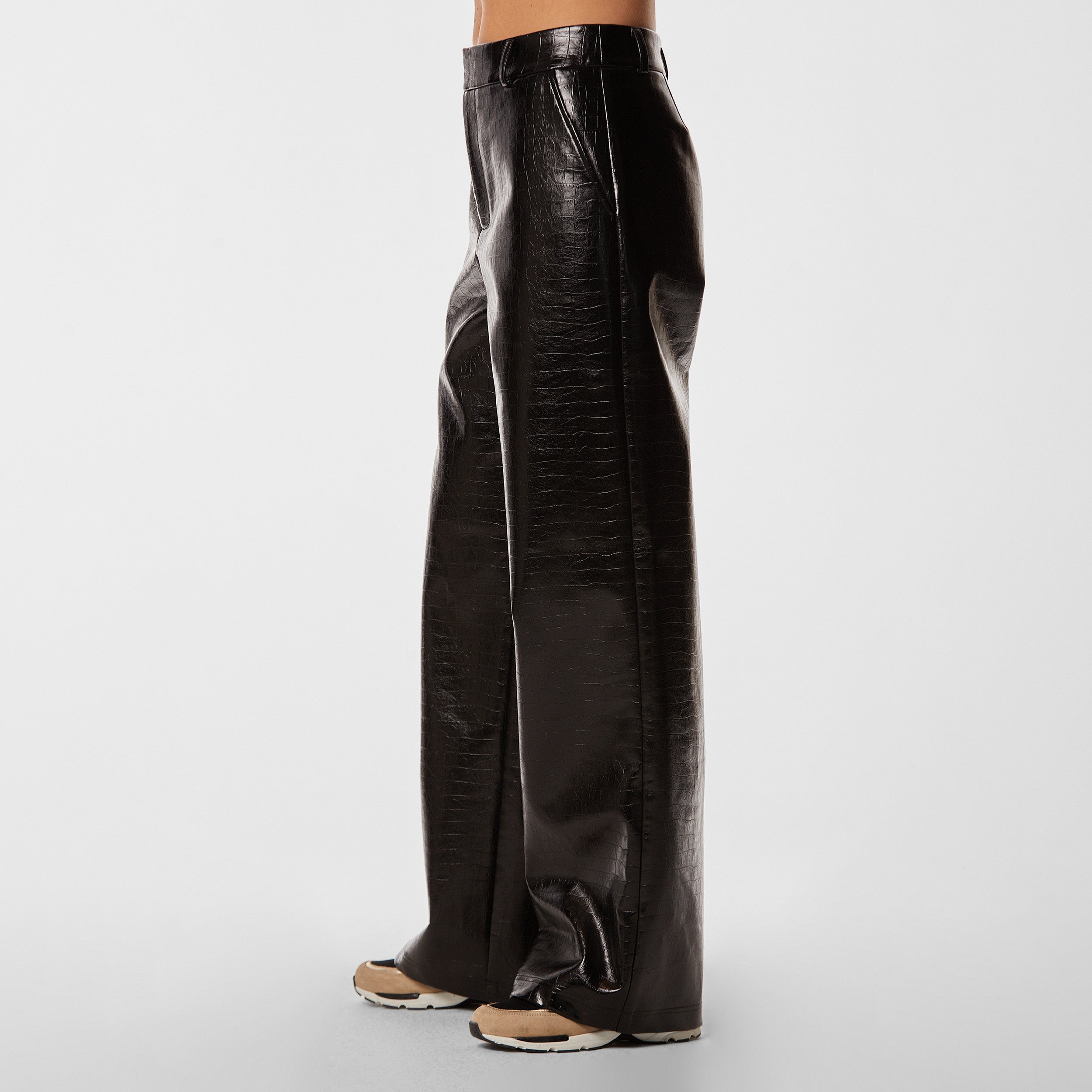 Side view of woman wearing black croco pattern embossed wide leg pant.