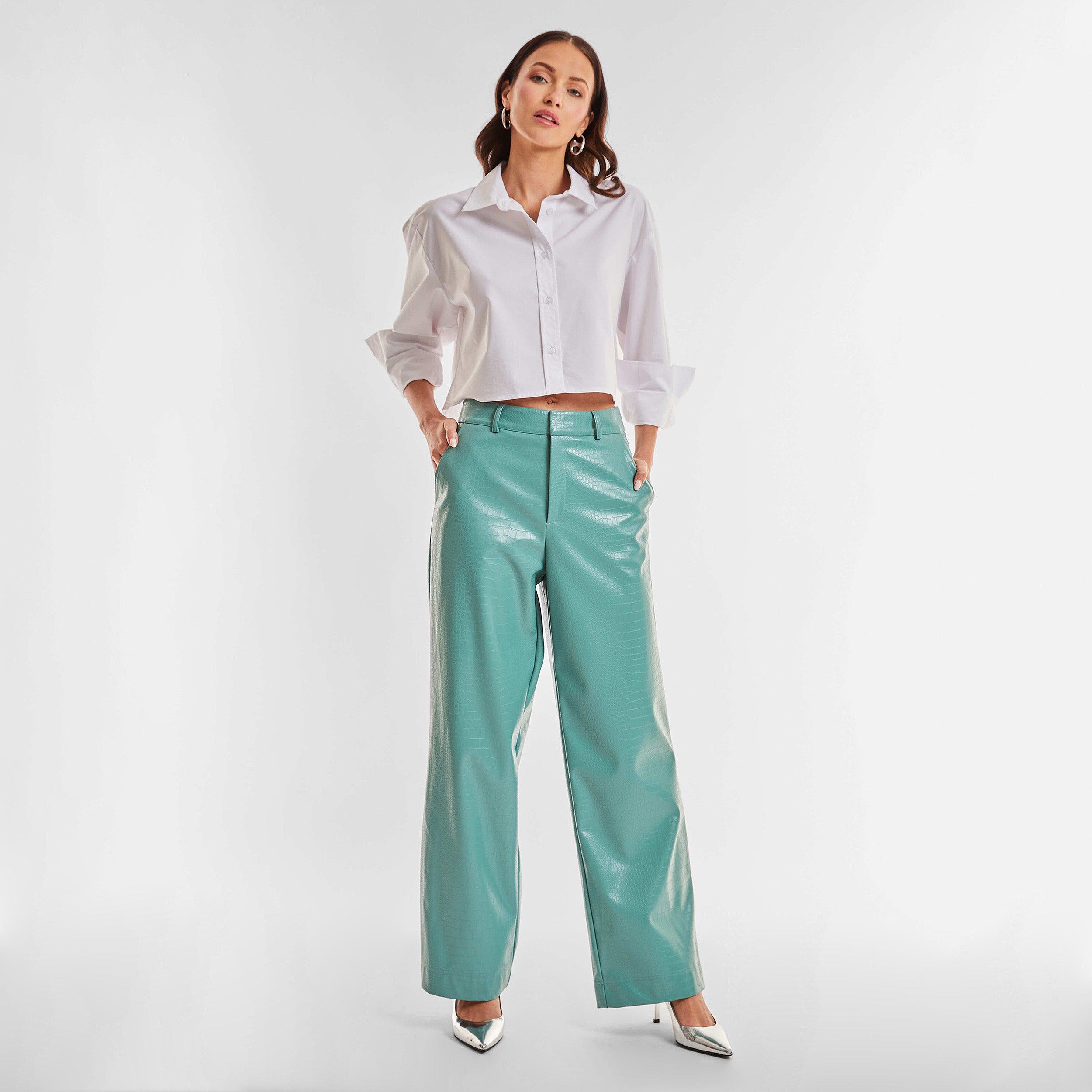 Full body front view of woman wearing sage colored faux leather croco pattern embossed wide leg pant and cropped white button up shirt
