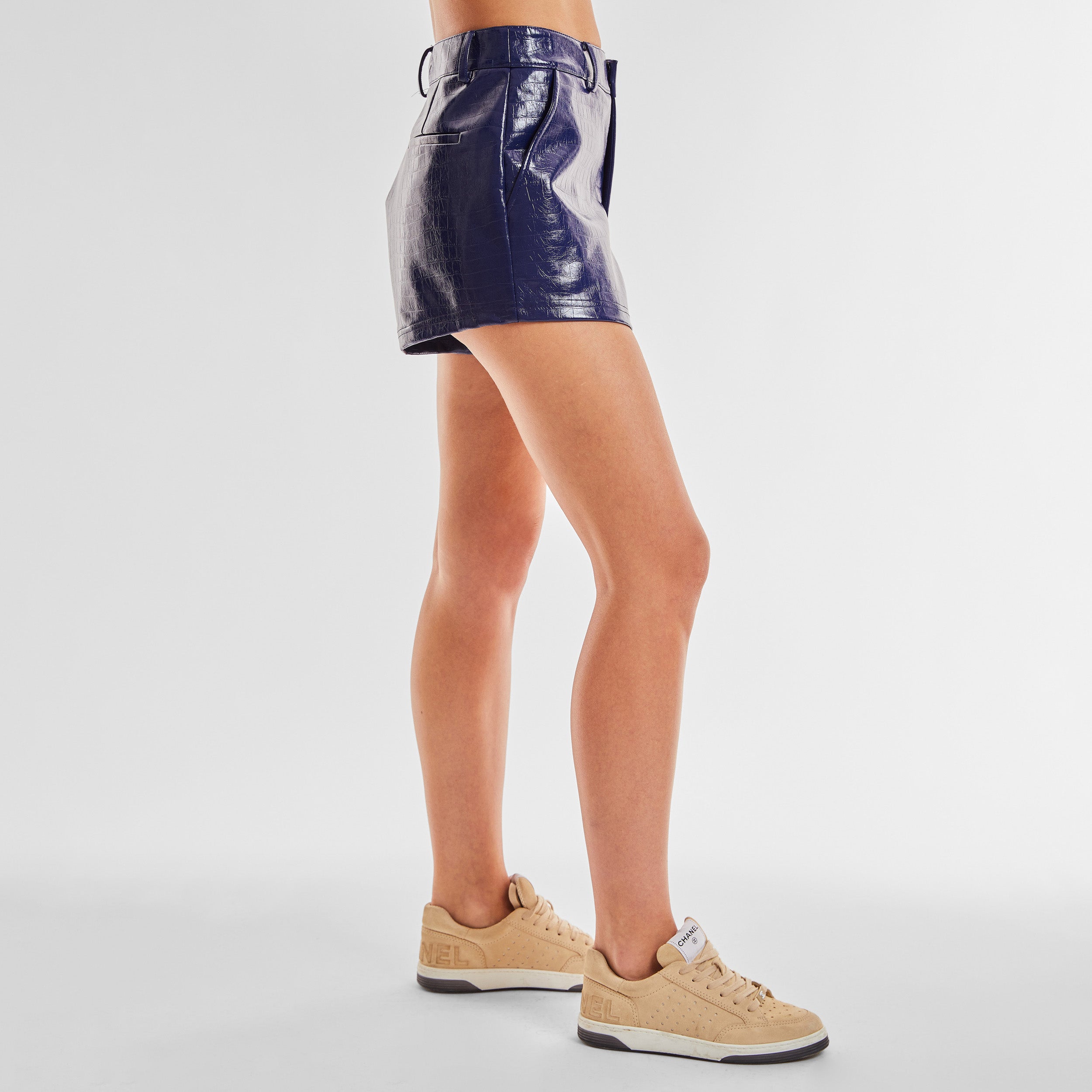 Side view of woman wearing blue faux leather short with croco embossed pattern.