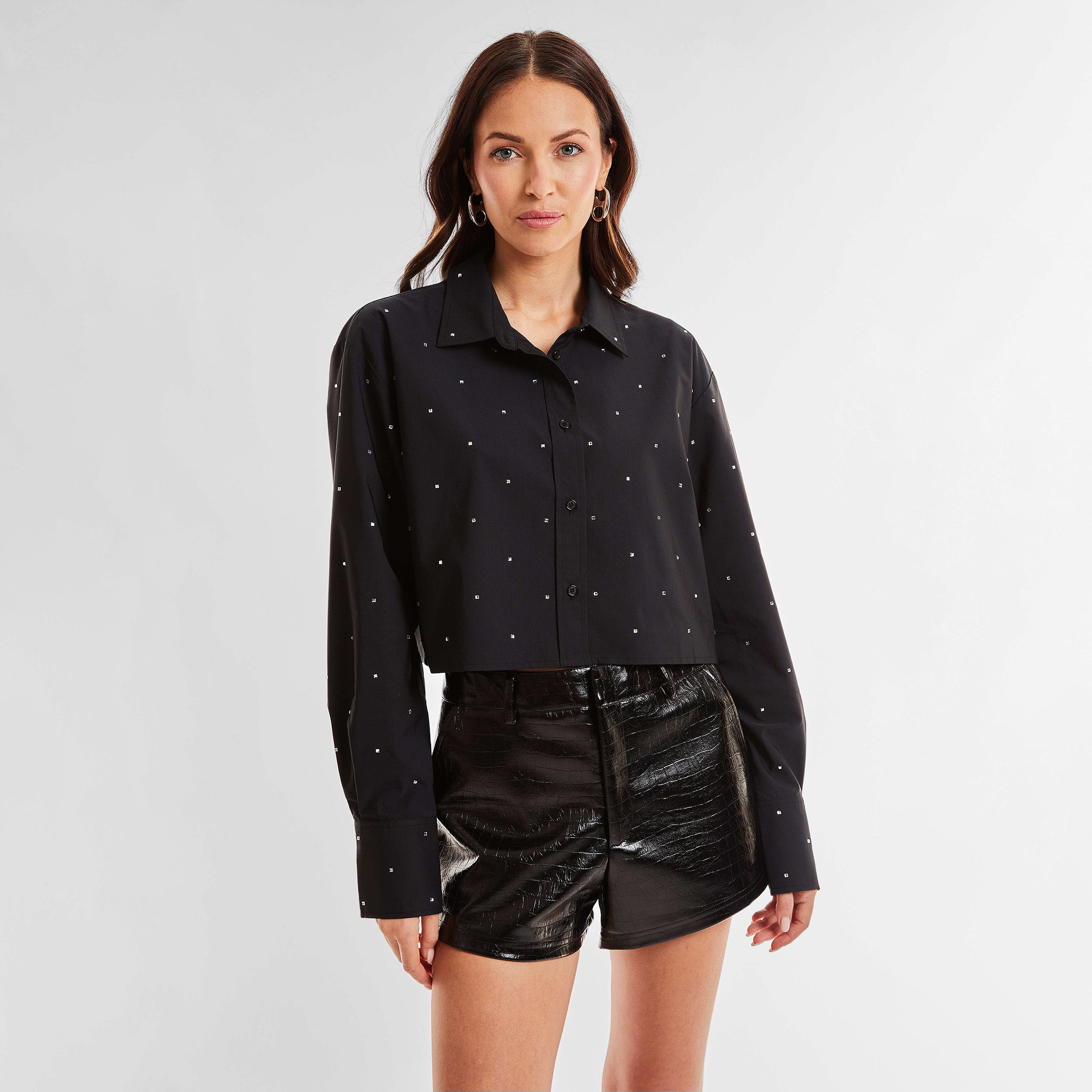 Front view of woman wearing a black cropped button down shirt with crystal embellishments.