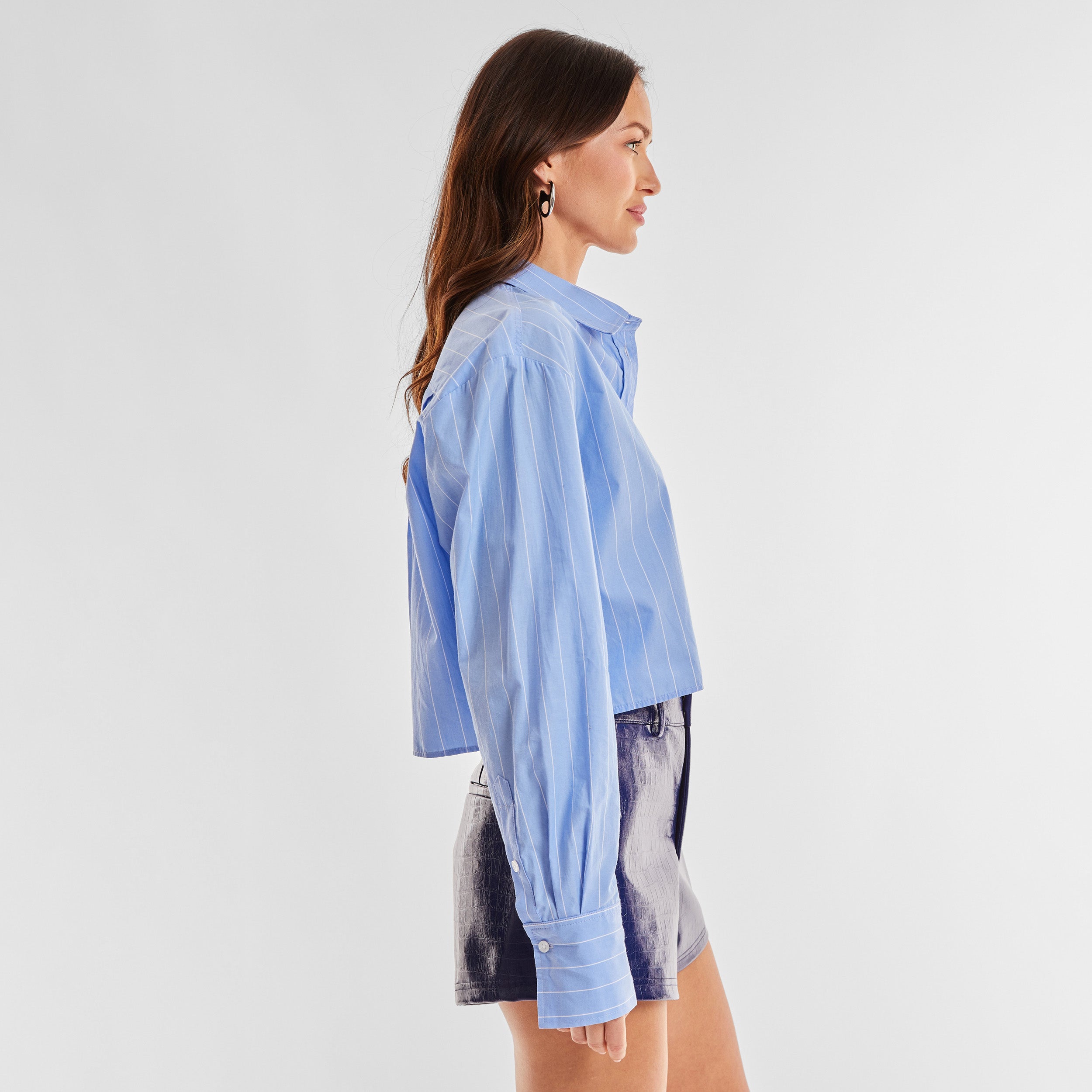 Side view of woman wearing a blue buttondown shirt with white stripes