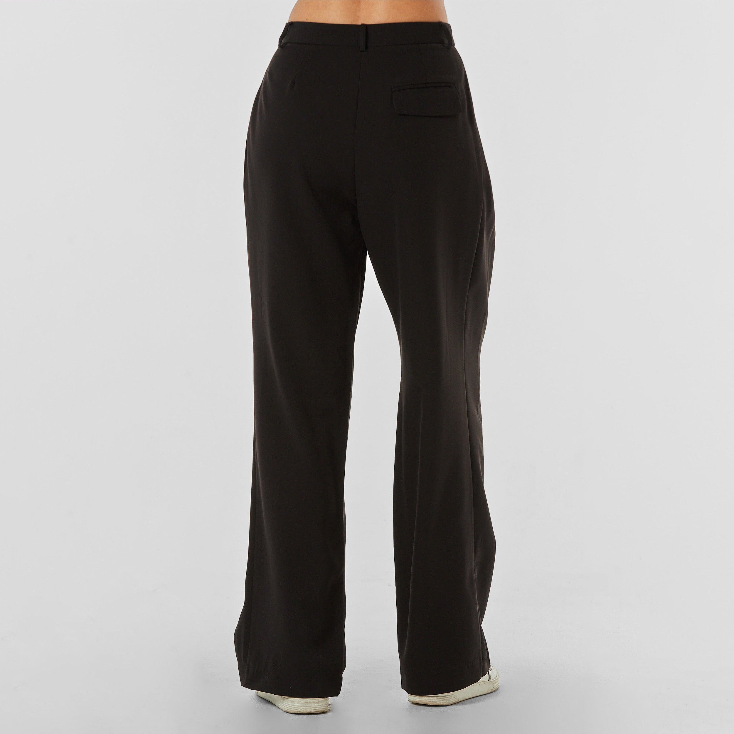 Rear view of woman wearing pleated black trousers with stretch fabric